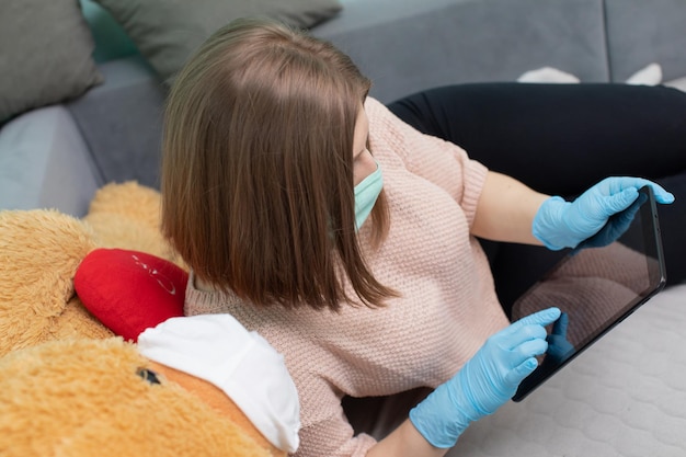 La jeune fille apprend pour l'examen avec le grand ours en peluche. Ils portent tous les deux des protecteurs.