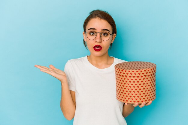 Jeune fille arabe maigre tenant une boîte de Saint Valentin surpris et choqué.