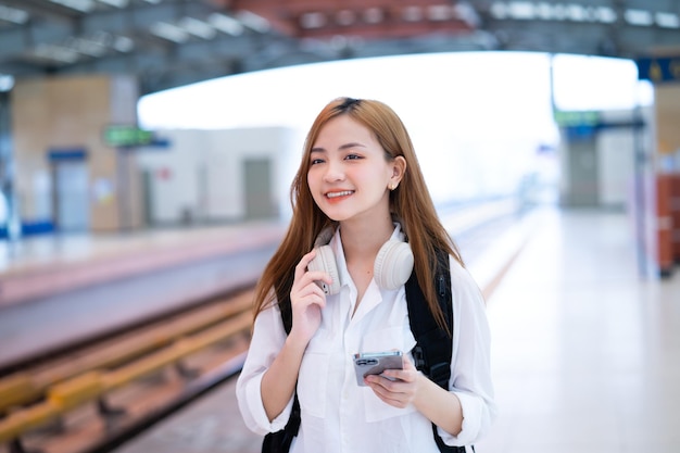 Jeune fille asiatique attendant le train à la gare