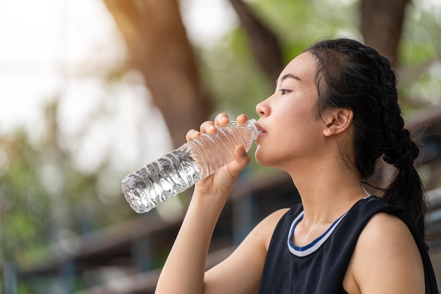 Jeune fille asiatique buvant de l'eau après avoir fait du jogging concept sain et sportif