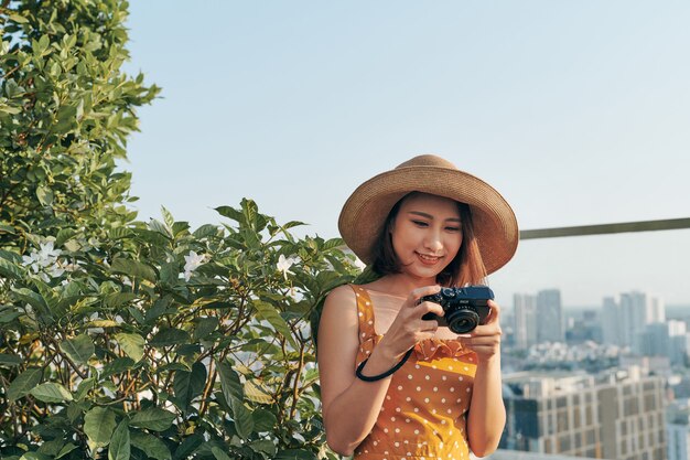 Jeune fille asiatique debout sur le toit et utilisant l'appareil photo pour prendre une photo. Notion d'été.