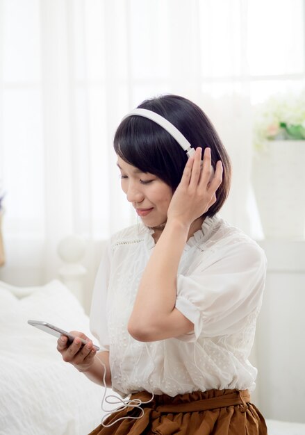 Jeune fille asiatique écoutant de la musique à la maison