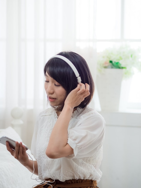 Jeune fille asiatique écoutant de la musique à la maison