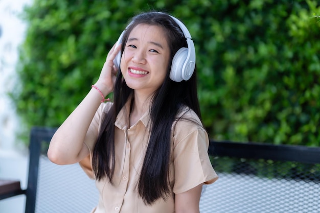 Photo jeune fille asiatique avec des écouteurs sans fil blancs et écoutant de la musique