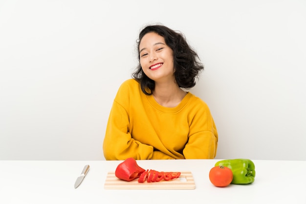 Jeune fille asiatique avec des légumes dans une table en riant