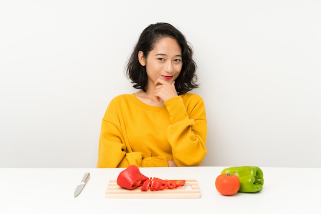 Jeune fille asiatique avec des légumes dans une table en riant