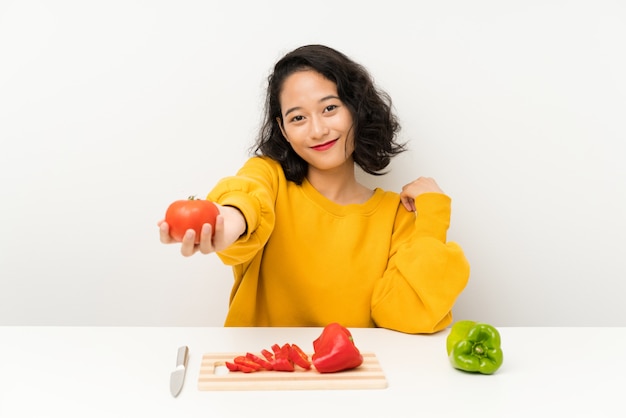 Jeune fille asiatique avec des légumes dans une table