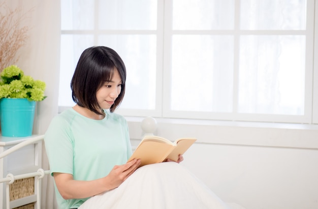 Jeune fille asiatique lisant un livre au lit