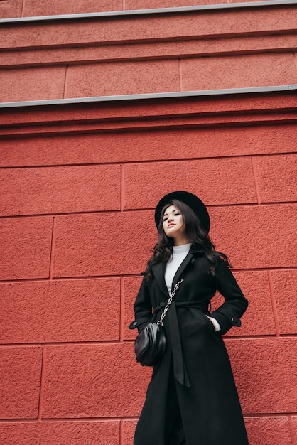 Jeune fille asiatique en manteau sombre et chapeau