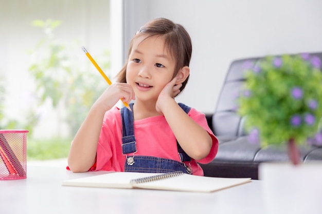 Jeune fille asiatique mignonne heureuse aime travailler sur son écriture dans son salon