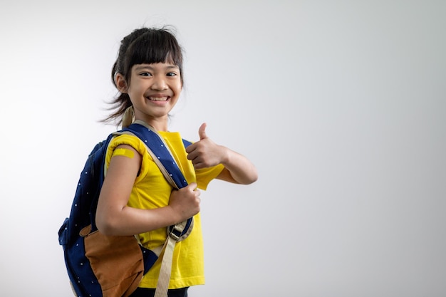 Jeune fille asiatique montrant son bras avec un bandage jaune après avoir été vaccinée ou vaccinée, vaccination des enfants, concept de vaccin delta covid