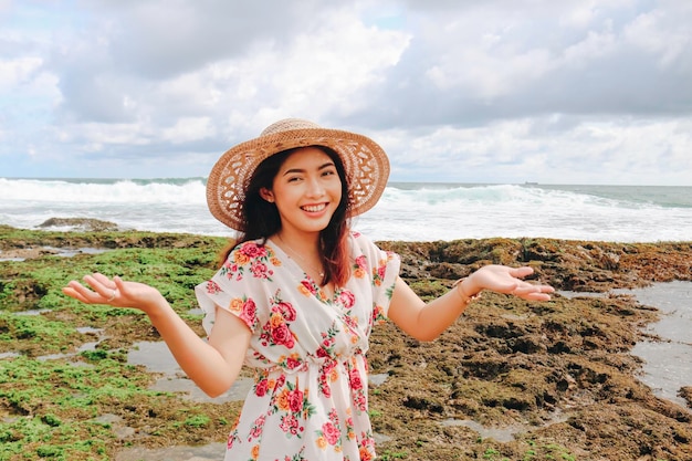 Une jeune fille asiatique portant un chapeau de plage se détend sur la plage de ciel bleu à Gunungkidul Indonésie