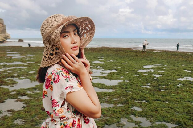 Une jeune fille asiatique portant un chapeau de plage se détend sur la plage de ciel bleu à Gunungkidul Indonésie