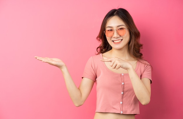 Jeune fille asiatique portant des lunettes avec une expression joyeuse sur un rose