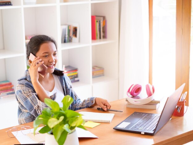 Jeune fille asiatique utilisant l'étude de téléphone intelligent à la maison