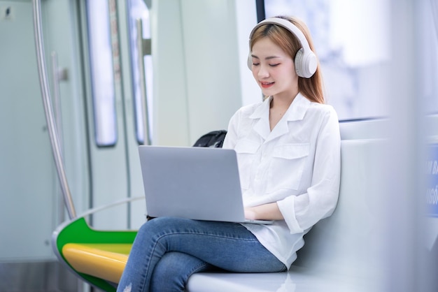 Jeune fille asiatique utilisant un ordinateur portable pour travailler dans le train