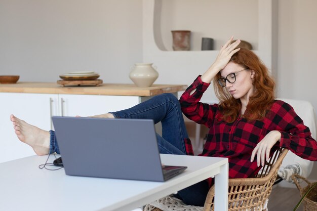 Jeune fille assez rousse parlant à l'aide d'un ordinateur à la maison dans la cuisine