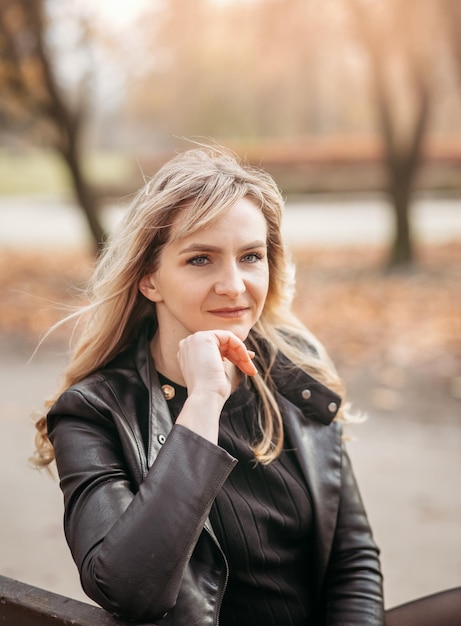 Jeune fille assise sur un banc dans un parc un jour d'automne