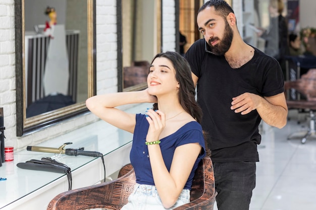 Jeune fille assise sur une chaise et un coiffeur lui coupant les cheveux Photo de haute qualité