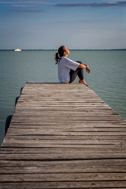 Photo jeune fille assise sur la jetée en bois