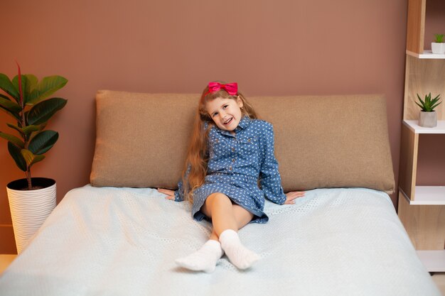 Jeune fille assise sur le lit dans la chambre