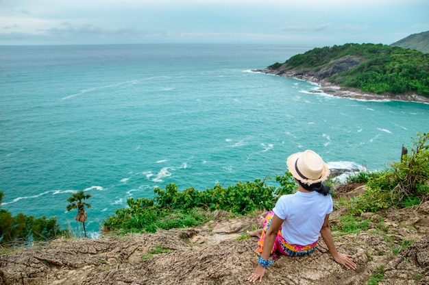 La jeune fille assise sur les rochers en regardant la belle mer bleue