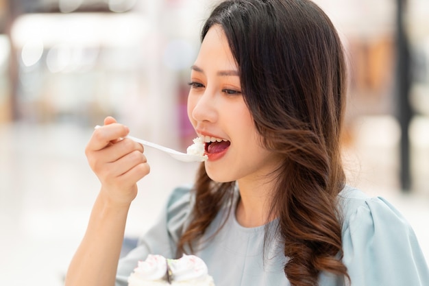 Jeune fille assise seule, manger un gâteau à la crème au centre commercial