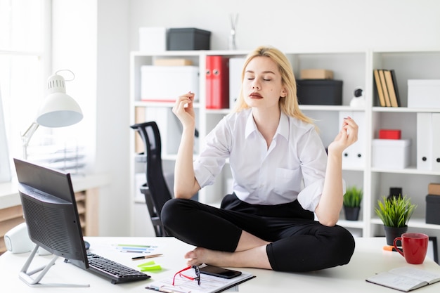 Une jeune fille assise sur une table dans le bureau.