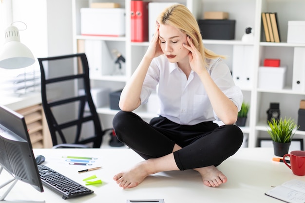 Une jeune fille assise sur une table dans le bureau.