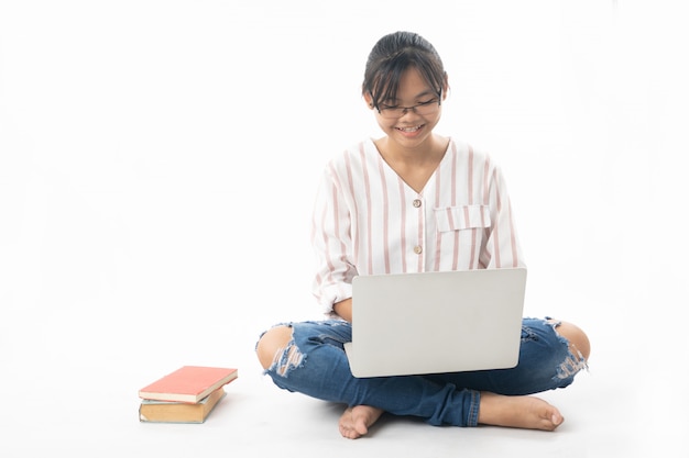 Jeune fille assise et utilisant un ordinateur portable isolé sur blanc