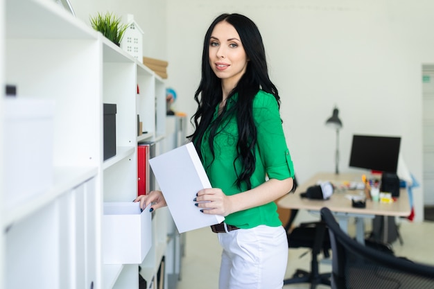 Une jeune fille au bureau sort une boîte blanche.