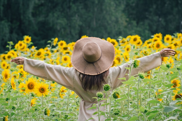 Jeune fille au chapeau sur un champ de tournesols