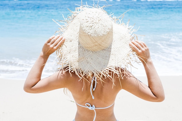 Photo jeune fille au chapeau de paille sur la plage