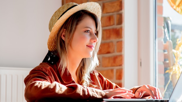 Jeune fille au chapeau à la recherche d'Internet via un ordinateur portable pour des vacances d'été