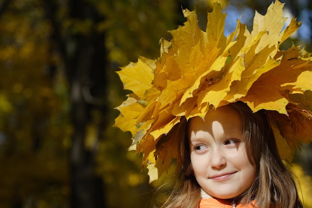 Jeune fille au parc avec diadème de feuilles d'érable jaune