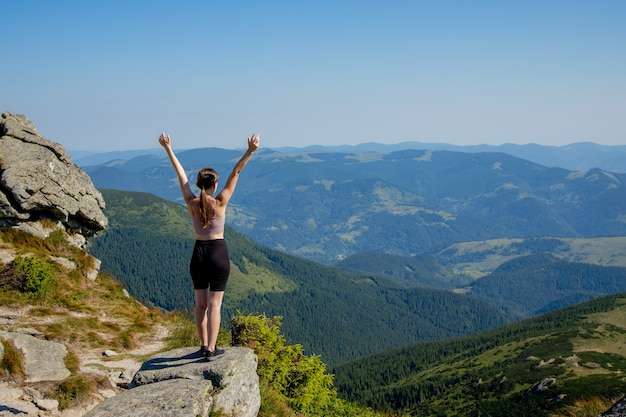 Photo la jeune fille au sommet de la montagne leva les mains sur le ciel bleu