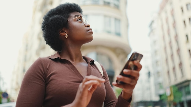 Jeune fille aux cheveux afro à la peau foncée debout à l'extérieur