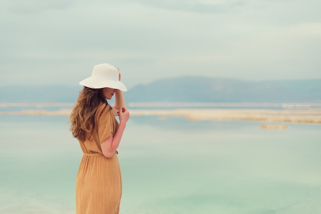 Jeune fille aux cheveux blonds brillants va au bord de la mer