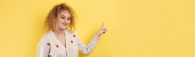 Photo une jeune fille aux cheveux bouclés pointe d'un geste sur un fond de studio