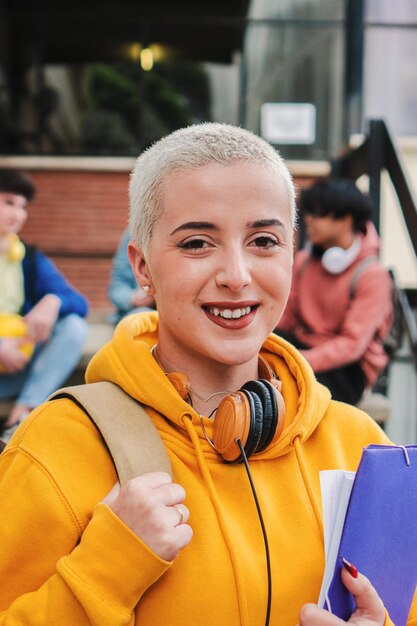 Photo une jeune fille aux cheveux courts regarde la caméra sur le campus.