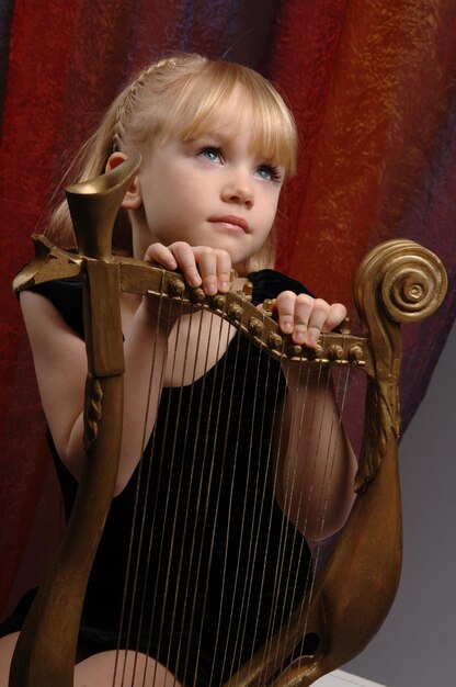 Une jeune fille aux yeux bleus et un instrument de musique.