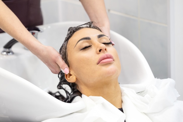 La jeune fille aux yeux fermés se lave les cheveux dans un salon de beauté