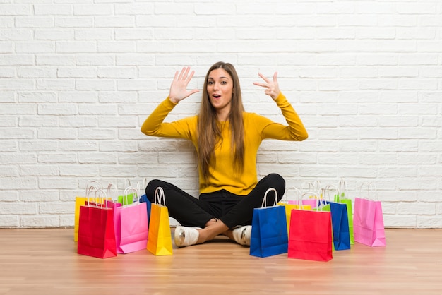 Jeune fille avec beaucoup de sacs à provisions comptant huit avec les doigts