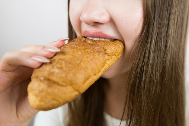 Une jeune fille belle mangeant un croissant en gros plan photo de récolte bouche féminine mangeant un croissant