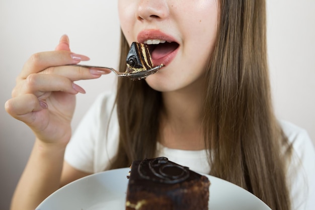 Une jeune fille belle mangeant un gâteau en gros plan photo de récolte de la bouche d'une femme mangeant un morceau de gâteau