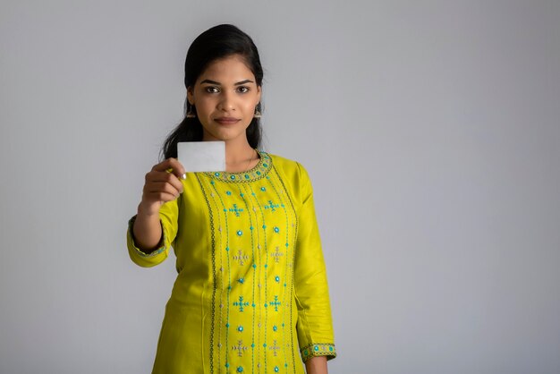 Jeune fille belle souriante posant avec une carte de crédit sur fond gris.