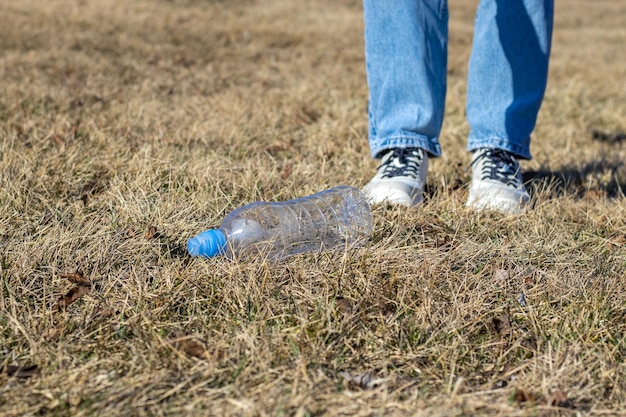 une jeune fille bénévole ramasse les ordures de l'herbe sèche dans une collecte de déchets de parc public