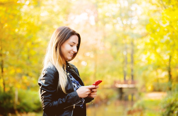 Jeune fille blanche à l'aide d'un téléphone portable dans un parc