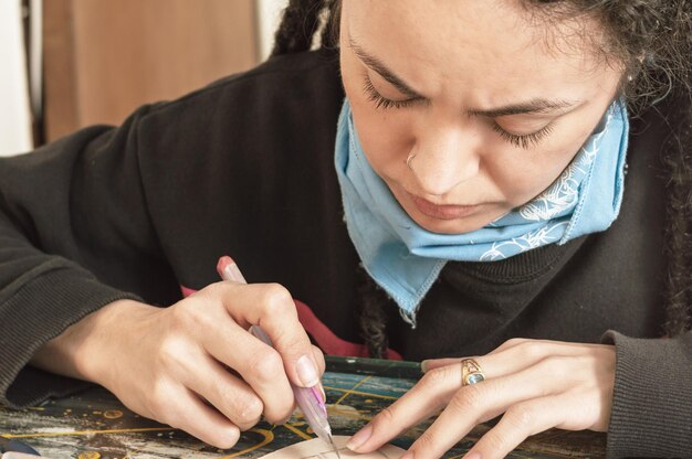 Jeune fille blanche directrice artistique latina avec un froncement de carton coupant avec un cutter