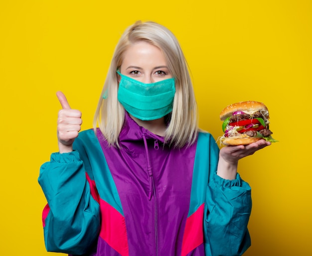 Jeune fille blonde au masque avec burger